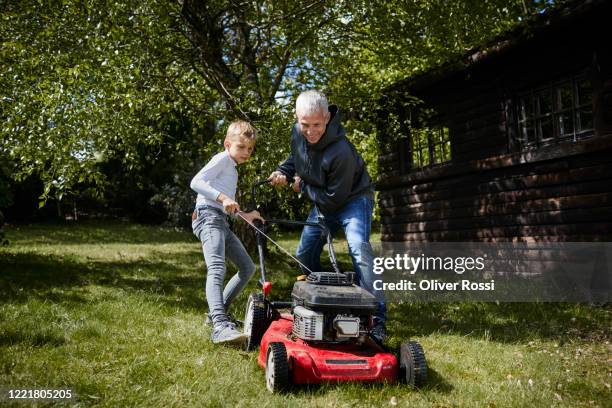 father and son mowing lawn in garden together - mowing lawn stock pictures, royalty-free photos & images