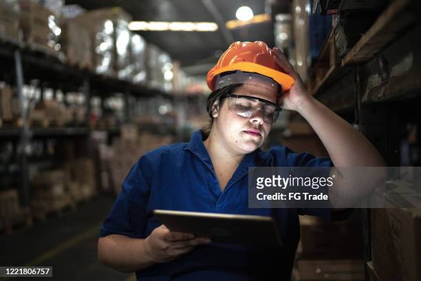 ongerust gemaakte werknemer die bij een pakhuis werkt - wrong job stockfoto's en -beelden