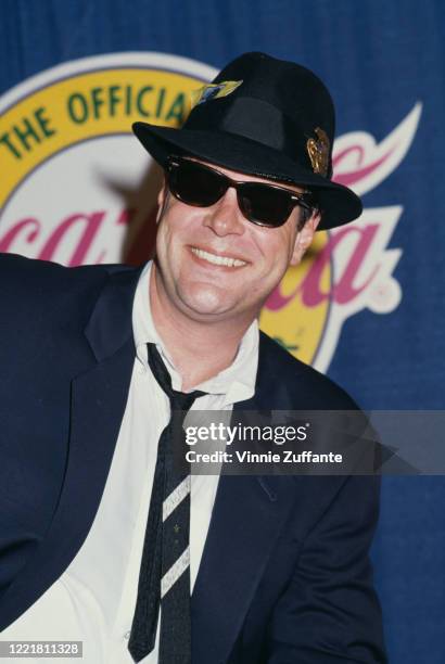 Canadian actor and comedian Dan Aykroyd wearing a trilby, with tickets in the band, his shirt open at the collar and the tie worn loose, and...