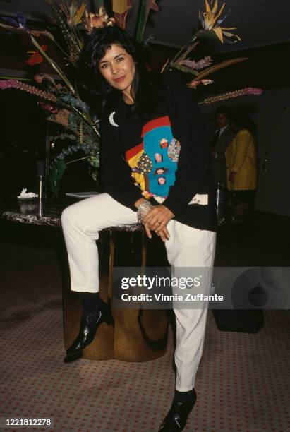 Cuban actress and singer Maria Conchita Alonso wearing a black sweater with a coloured pattern on the chest, and white trousers, circa 1995.