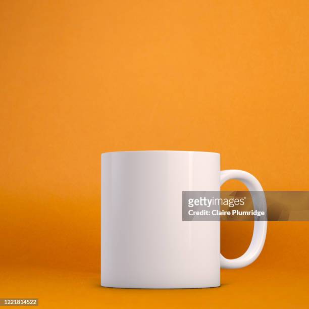 white mug mockup on a orange background. perfect for businesses selling mugs, just overlay your quote or design on to the image. - mug photos et images de collection