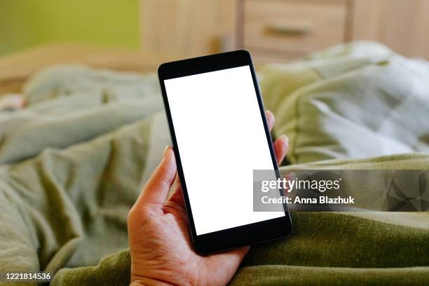 woman holding cell phone with white blank screen at home in bed, shop online, stay at home concept - bed phone stock-fotos und bilder