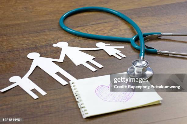 healthcare insurance for family. stethoscope, pink heart written on paper and family on wooden background - medical insurance stock pictures, royalty-free photos & images