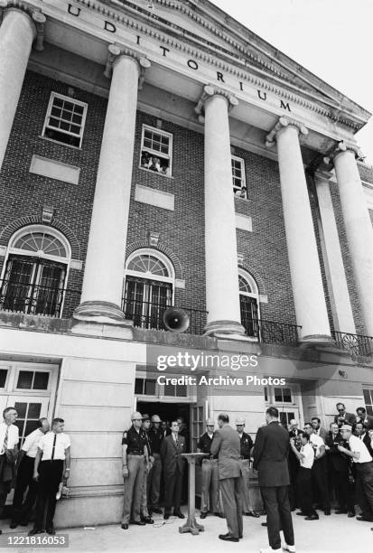 American politician George Wallace , Governor of Alabama, stands at the door of the Foster Auditorium, watched by the US Deputy Attorney General...