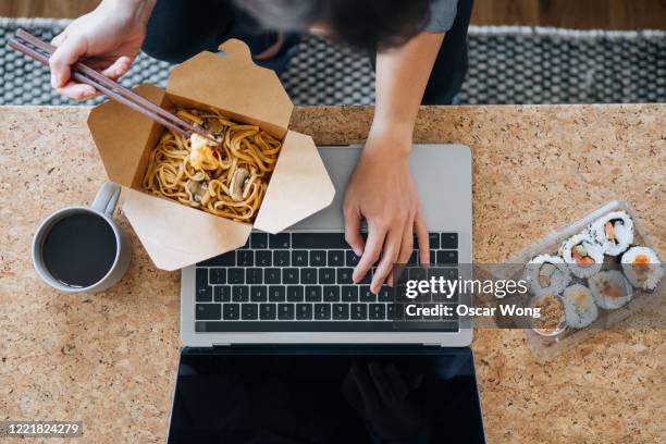 young woman eating takeaway food while using laptop - lunch top view stock pictures, royalty-free photos & images