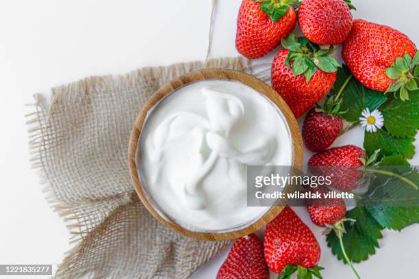 yogurt in a bowl with spoons,healthy breakfast with fresh greek yogurt and strawberry on background - strawberry and cream stock-fotos und bilder