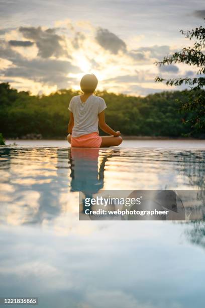 woman meditating on pool's edge - lotus position imagens e fotografias de stock
