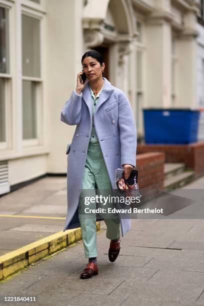 Caroline Issa wears a pastel blue wool coat, green pants, brown leather shoes, during London Fashion Week February 2020 on February 17, 2020 in...