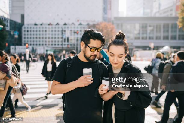 paar mit smartphone, um die stadt zu erkunden - bezirk shibuya stock-fotos und bilder