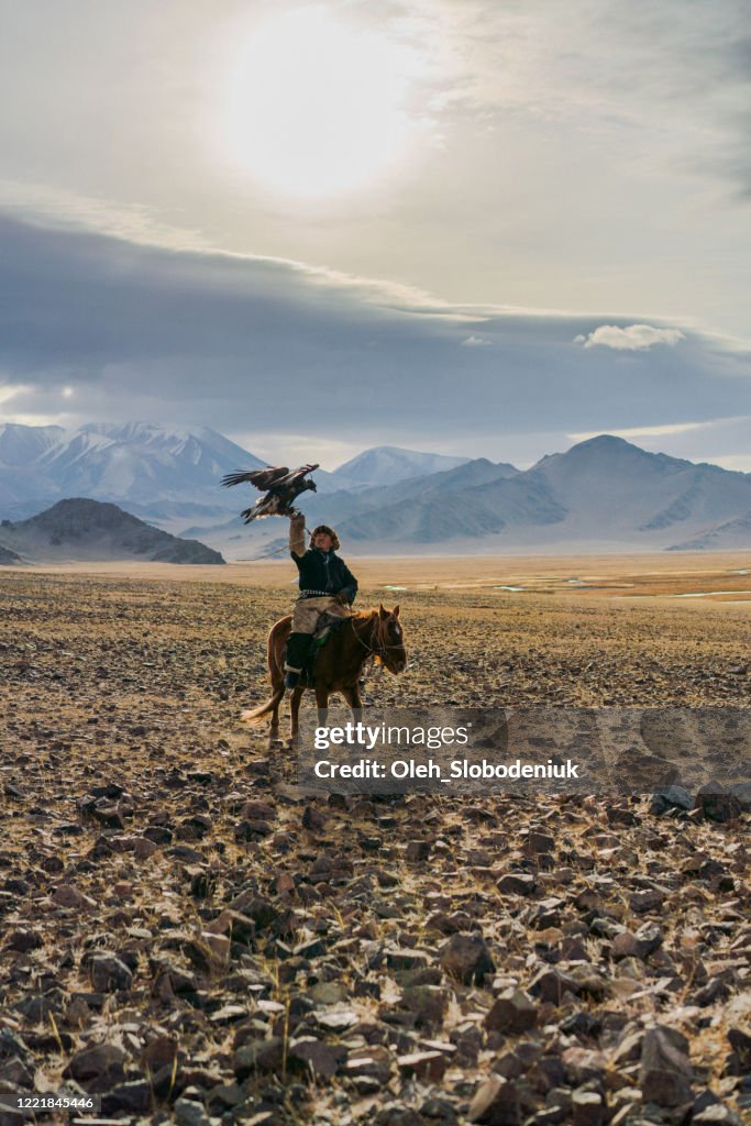 Eagle hunter on horse in desert in Mongolia