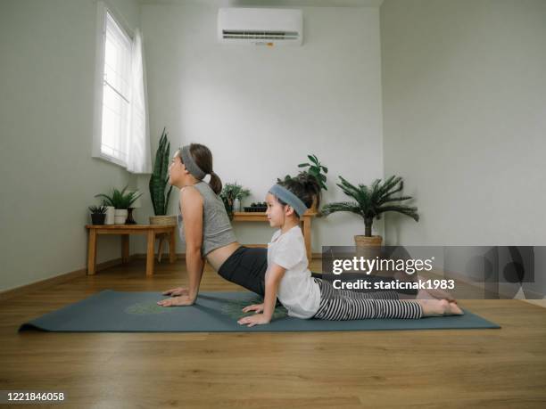 jonge moeder en dochter die een oefeningen thuis maken. - opdracht om thuis te blijven stockfoto's en -beelden