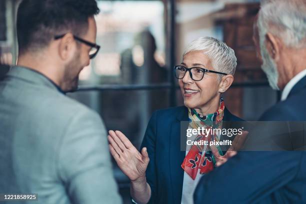 senior businesswoman talking to colleagues - short hair stock pictures, royalty-free photos & images