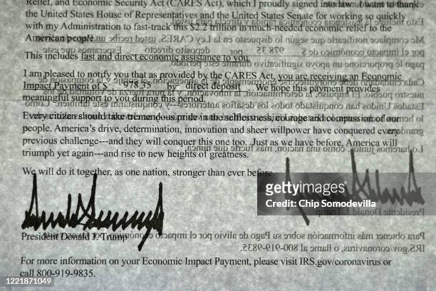 President Donald Trump's signature can be seen twice as light shines through a letter printed in both English and Spanish that was sent to people who...