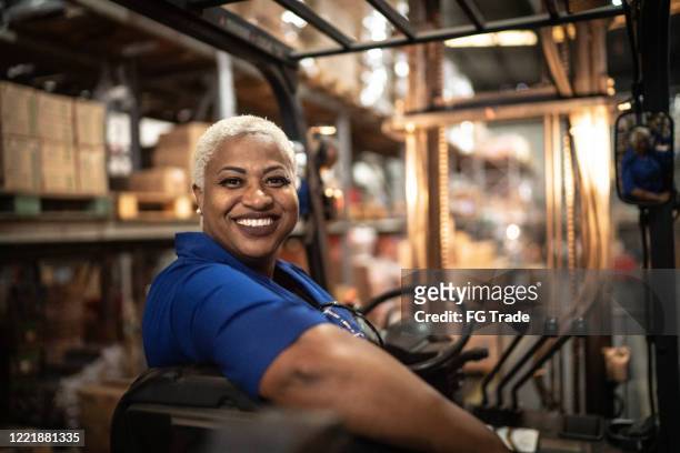 ritratto di lavoratrice alla guida di carrelli elevatori in magazzino - female supermarket foto e immagini stock