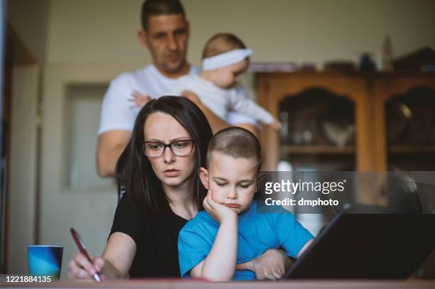 working mom using laptop as husband cares for baby - worried family stock pictures, royalty-free photos & images