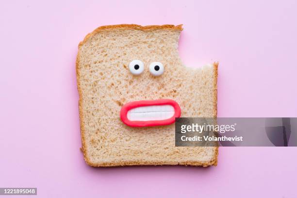 sliced bread with faces on pink background - eating bread stockfoto's en -beelden