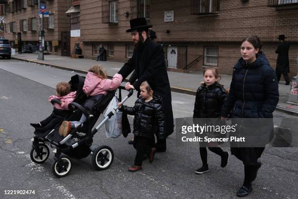 People walk through a Hasidic neighborhood on April 29, 2020 in the Brooklyn borough of New York City. Mayor Bill De Blasio lashed out on Twitter...