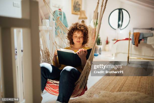 young woman home alone with herself, reading a book - hammock stock pictures, royalty-free photos & images