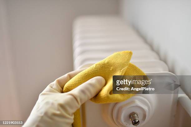 wiping down sufraces - heating radiator - yellow glove stock pictures, royalty-free photos & images