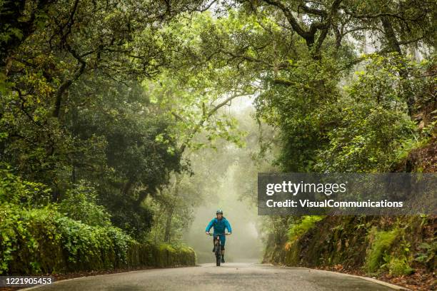 man on mountain bike riding in the middle of rural road. - sintra portugal stock pictures, royalty-free photos & images