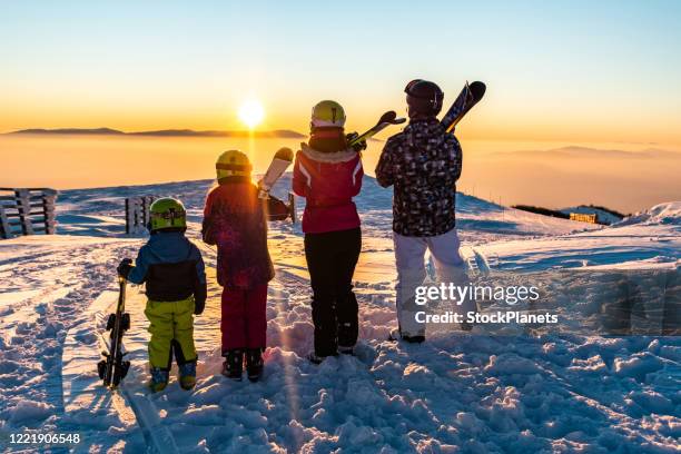 family looking at sunset from the top of mountain - family skiing stock pictures, royalty-free photos & images