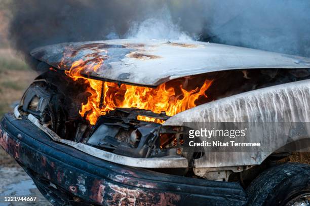 close-up of burning car engine after a frontal crash collision on the roadside with flame and smoke. - auto frontal stock pictures, royalty-free photos & images