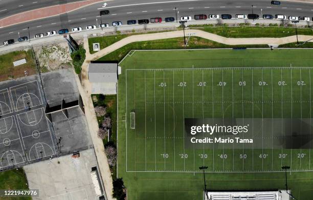 An aerial view of cars lined up to receive food distributed by the Los Angeles Regional Food Bank and the city, as basketball courts and a football...