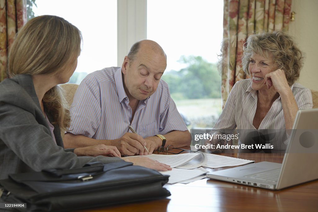 Senior couple signing documents with adviser
