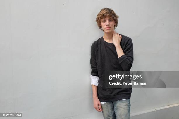 stylish, attractive young man wearing casual clothes against white wall, with mid length curly hair - medium length hair stock pictures, royalty-free photos & images