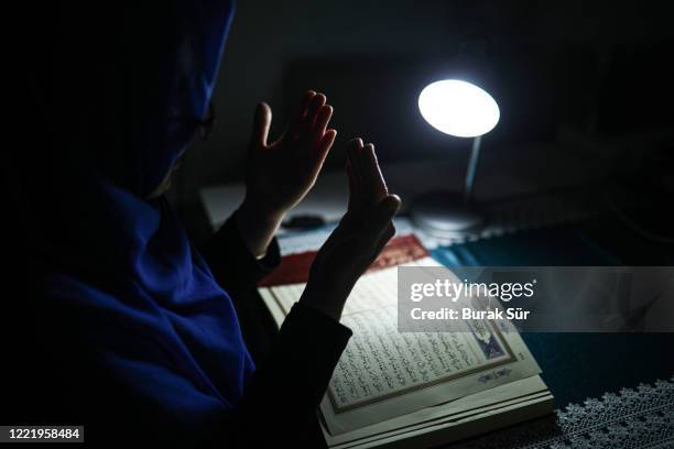 woman is reading quran in ramadan. she prays with her hands open and be thankful - koran stock pictures, royalty-free photos & images