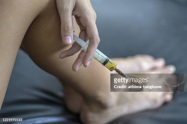 woman drug addict injecting herself with heroin. - iv drip womans hand stock pictures, royalty-free photos & images