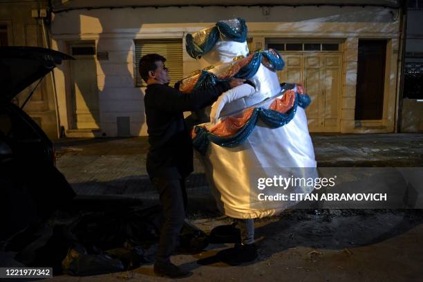 Alexis helps his wife Estela to take off the cake costume, after delivering it to a 15-year-old boy for his birthday, in Montevideo on June 22 amid...
