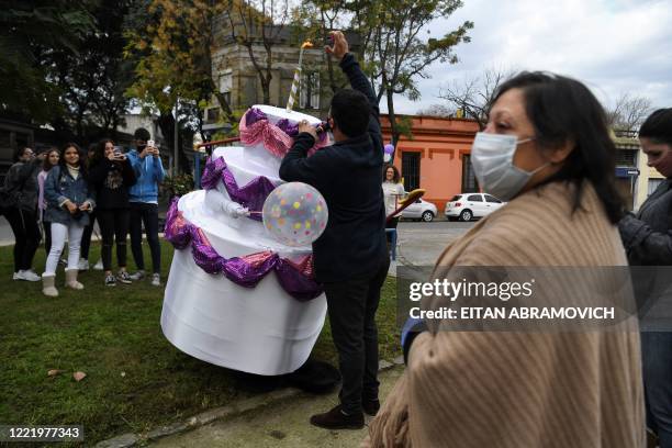 Alexis lights a candle on a human cake given to a 15-year-old for her birthday as neighbors surround it, in Montevideo on June 12, 2020. - Due to the...