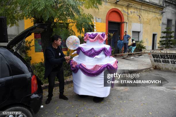 Alexis gives a balloon to his wife Estela , before deliving it to a 15-year-old for her birthday, in Montevideo on June 12, 2020. - Due to the...