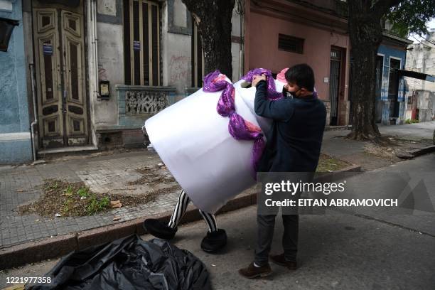 Alexis takes off a human cake costume from his wife Estela, after deliving to a 15-year-old for her birthday, in Montevideo on June 12, 2020. - Due...