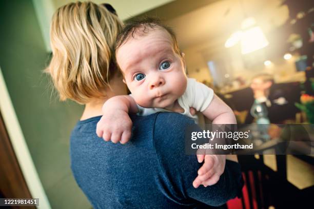 super cute baby girl looking at camera over mother's shoulder - funny face baby stock pictures, royalty-free photos & images