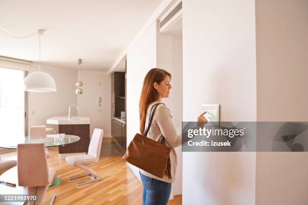 donna che attiva il sistema di sicurezza della casa intelligente prima di partire - control pants foto e immagini stock