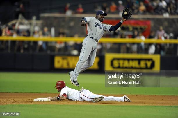 Orlando Hudson of the San Diego Padres catches a throw from the catcher as he jumps over a sliding Ryan Roberts ##14 of the Arizona Diamondbacks at...