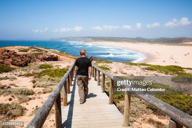 tourist walking on boardwalk to the beach, algarve, portugal - zuid europa stockfoto's en -beelden