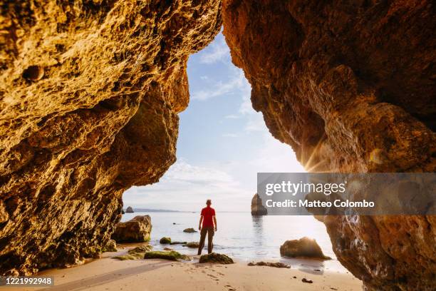 man enjoying sunrise from a cave, algarve, portugal - distrito de faro portugal fotografías e imágenes de stock