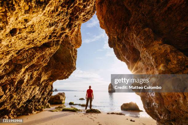 man enjoying sunrise from a cave, algarve, portugal - distrito de faro portugal imagens e fotografias de stock