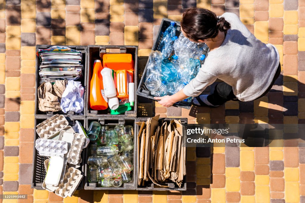 Woman organizes garbage containers for recycling.