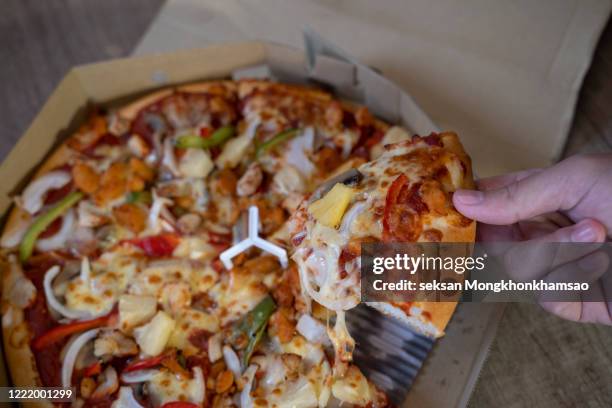 man picking up a lice of hot pizza. - pizza crispy stock-fotos und bilder