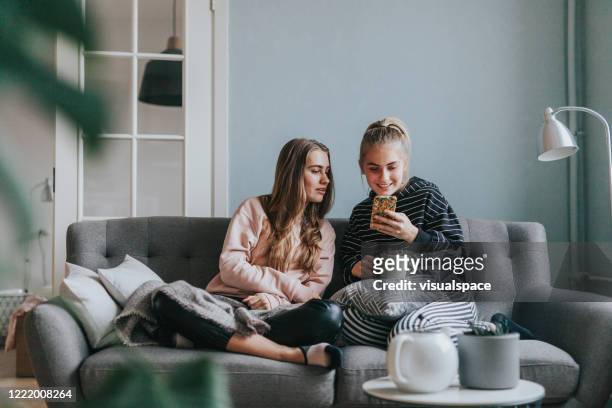 two teenage girls using smart phone at home on the couch - cute 15 year old girls stock pictures, royalty-free photos & images