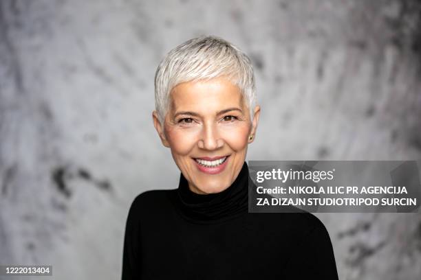 happy senior woman against grey background. - mature female models stock pictures, royalty-free photos & images
