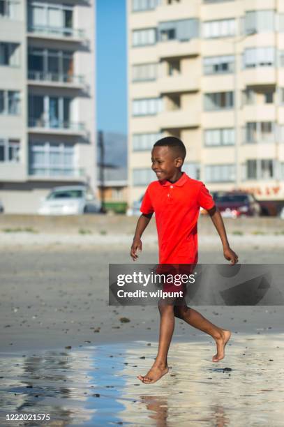 boy running barefoot on beach side view - running side view stock pictures, royalty-free photos & images