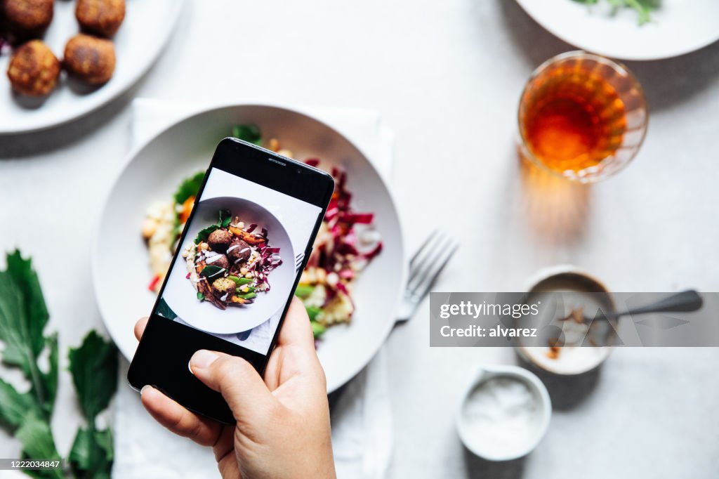 Chef tomando fotografía de un cuenco de falafel vegano sobre la mesa.