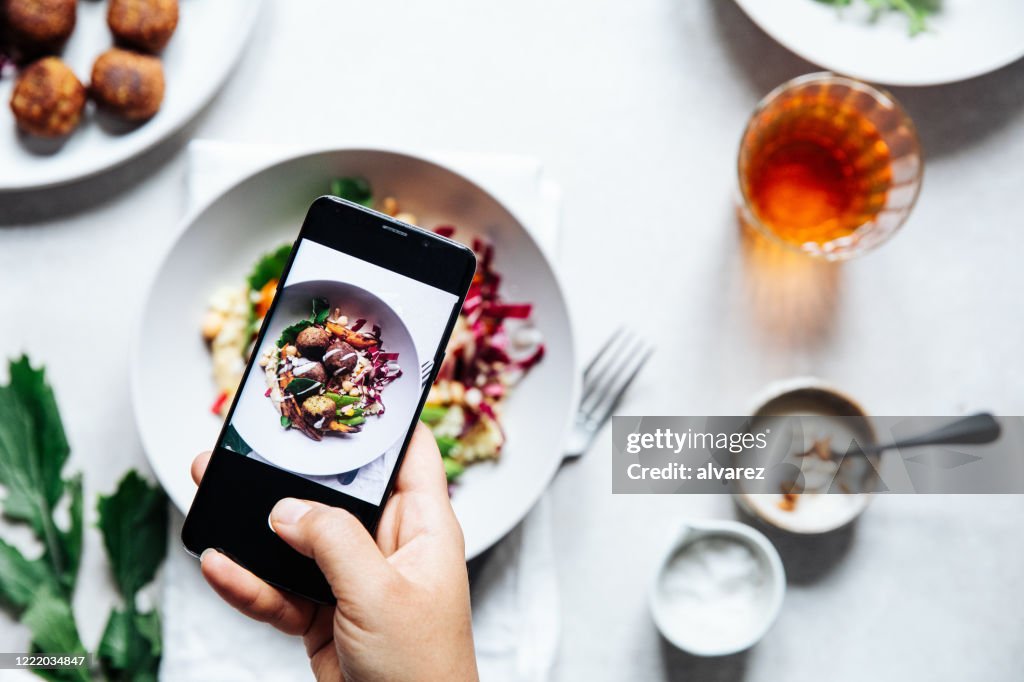 Chef prenant la photo du bol végétalien de falafel sur la table.