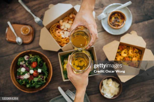 sharing takeaway meal on dining table - friends toasting above table stock-fotos und bilder