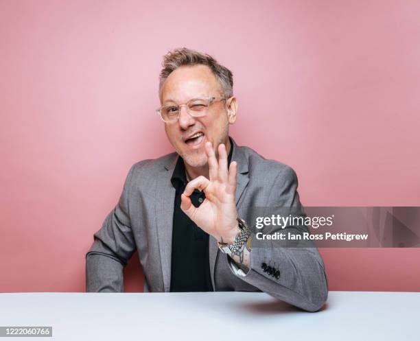 businessman on pink background making ok sign - augenzwinkern stock-fotos und bilder